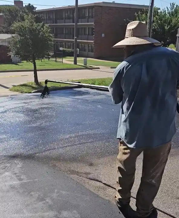 Man raking pothole repair compound and smoothing it